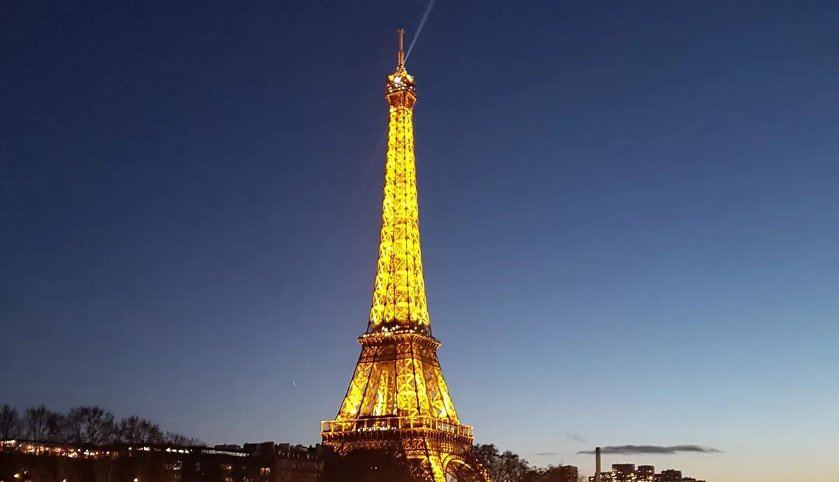 The Eiffel Tower glowing gold over the Seine at night